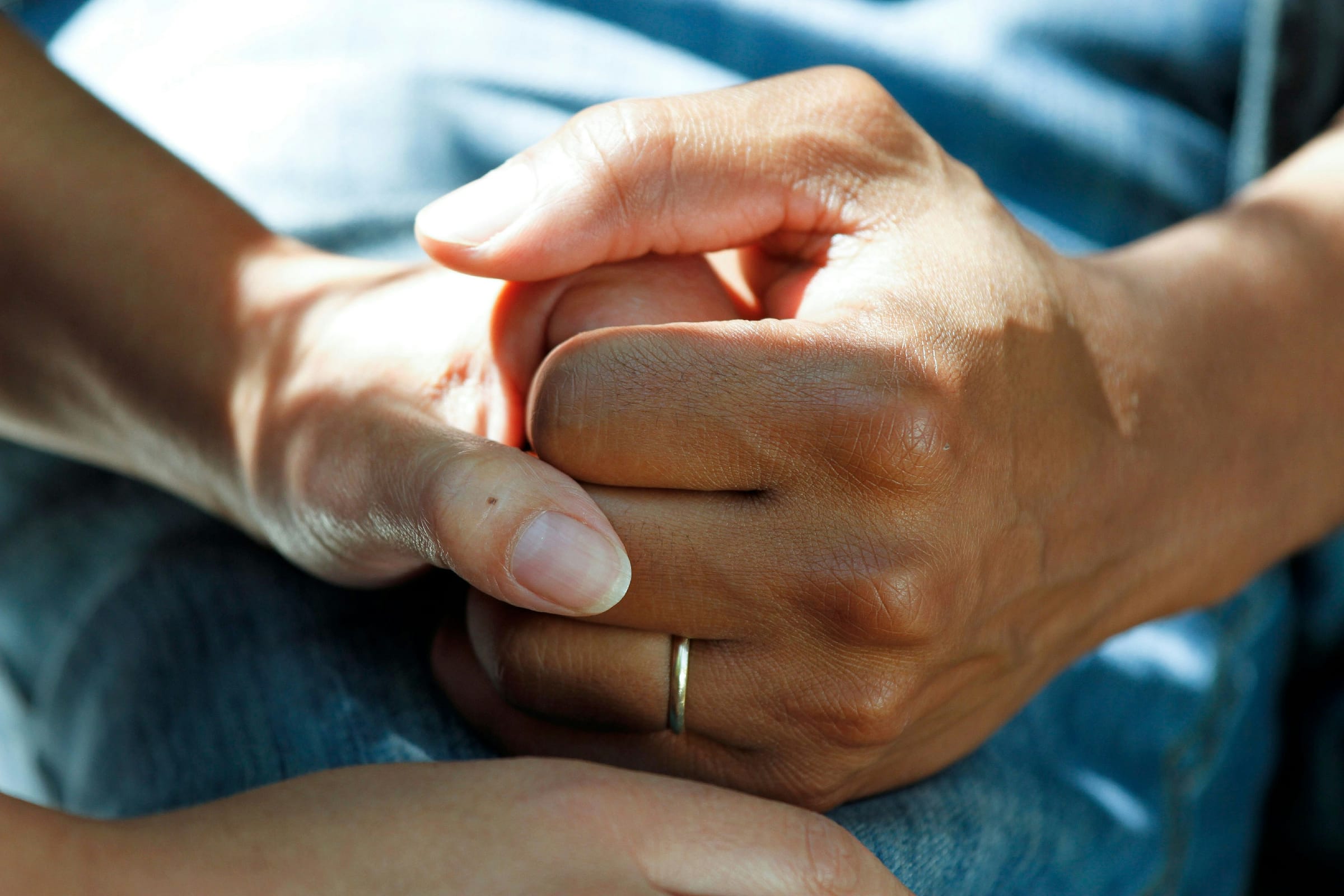 A caregiver's hand holding a client's hand