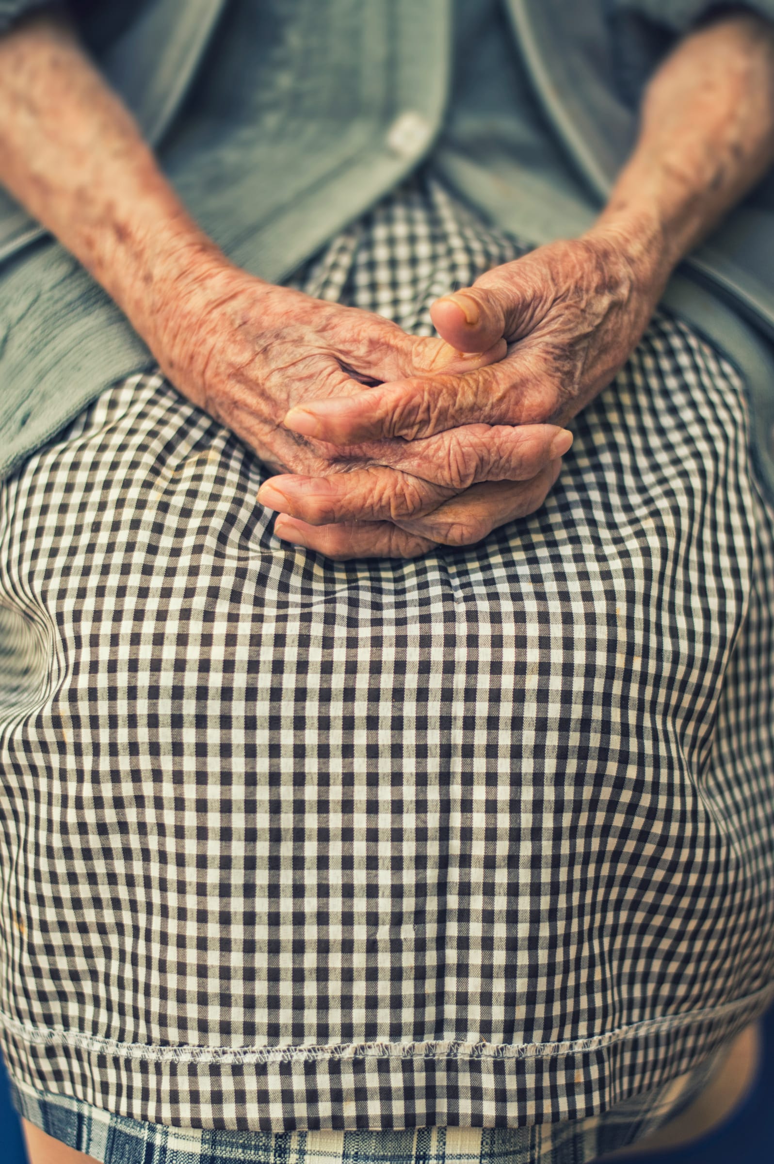 An older person's hands folded quietly in their lap