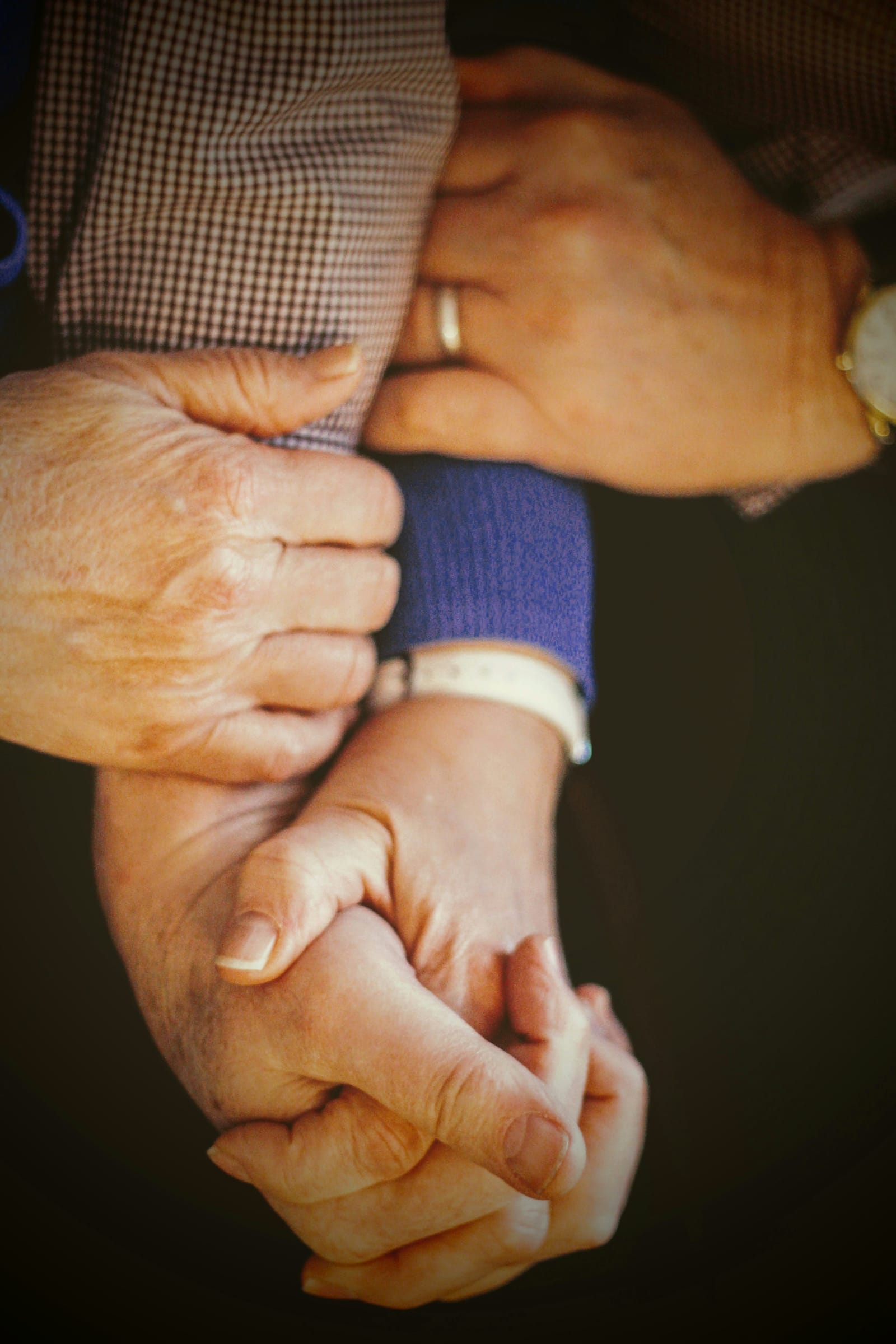 An older person's hands held in a younger person's hands